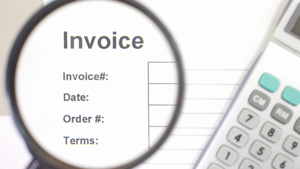 書面に印字された「Invoice」の文字が虫眼鏡で拡大されている写真