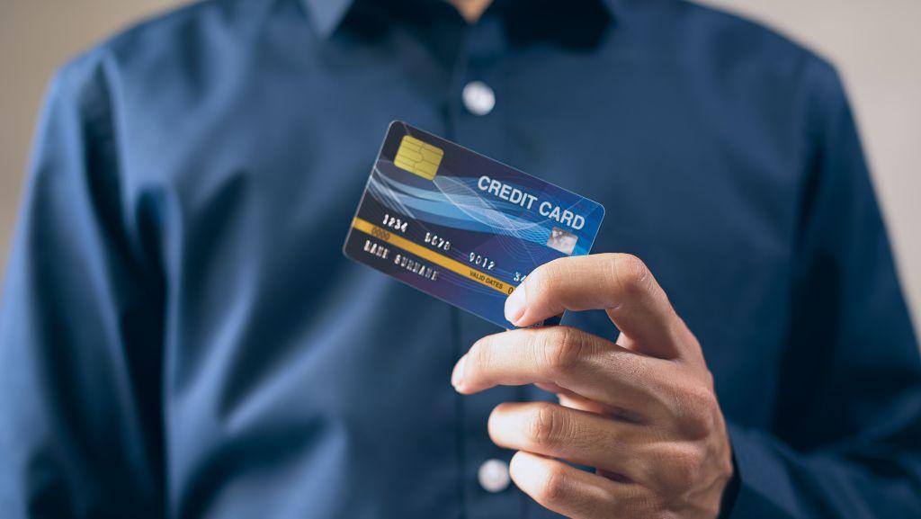 青いシャツの男性がクレジットカードを持っている写真